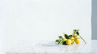 Freshly picked yellow lemons with green leaves scattered on white marble surface next to clear glass bowl, ideal for food styling, culinary content, and kitchen design projects.