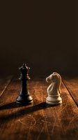 Chess pieces king and knight on wooden board representing strategy, competition and business leadership concepts for corporate presentations.