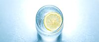 Glass of refreshing sparkling water with fresh lemon slice on icy surface, perfect for beverage, wellness, hydration, and food photography projects.