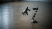 Vintage desk lamp with adjustable arm on concrete surface, suitable for office, workspace, and interior design projects.