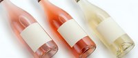 Three elegant rosé wine bottles with blank white labels arranged on white background, perfect for branding mockups and wine marketing materials.