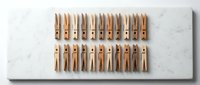 Wooden clothespins arranged in neat rows on white marble surface for laundry organization and household cleaning tasks.
