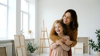 Happy mother and daughter embracing in bright modern home interior with natural light from large windows. Family bonding moment in minimalist living space.