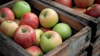 Fresh red and green apples in rustic wooden crates, natural organic produce with textured weathered wood boxes creating vintage farm market atmosphere.