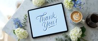 Digital tablet displaying Thank You message surrounded by white and blue hydrangea flowers with coffee cup on marble surface for gratitude expressions.