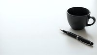 Black coffee cup and pen on white background for business workspace design and office branding materials.
