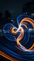 Long exposure light painting with swirling blue and orange neon trails creating abstract spiral patterns against dark urban cityscape background. Use for modern design, technology, energy concepts.