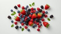 Fresh mixed berries collection with strawberries blueberries raspberries and blackberries scattered on white background for healthy eating concepts.