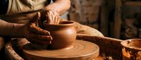 Skilled potter's hands shaping clay vessel on spinning wheel in traditional ceramic workshop. Artisan craftsmanship and handmade pottery creation process.