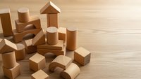 Natural wooden building blocks scattered on wood surface for educational play and creative construction activities.