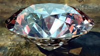 Brilliant cut diamond with blue and pink reflections resting on rough stone surface, showcasing facets, clarity and light dispersion in luxury jewelry setting.