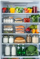 Open refrigerator filled with fresh vegetables, fruits, dairy products, bread and healthy food ingredients organized on shelves for meal preparation.
