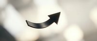 Black curved arrow pointing upward and right on soft blurred background suggesting growth, progress, and forward movement for business presentations.