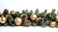 Festive winter garland with golden baubles and natural pine cones arranged on evergreen branches against white background, creating elegant holiday decor.