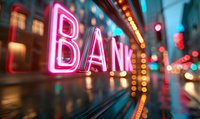 Pink neon bank sign glowing in urban night setting with bokeh lights and reflective wet surface creating atmospheric street photography mood.