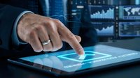 Businessman hand touching digital tablet with glowing financial charts and data analytics interface for modern business technology solutions.