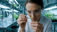 Female scientist examining plant sample with tweezers in modern laboratory greenhouse for botanical research and agricultural development.
