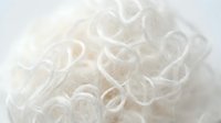 Clear rubber bands or elastic hair ties arranged in a pile, suitable for hairstyling, organization, and beauty product photography.