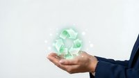Businessman hand holding glowing green recycling symbol with light particles on white background, representing sustainability and environmental responsibility.