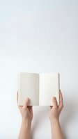 Female hands holding open blank book with empty pages against white background for reading education and literature concepts.