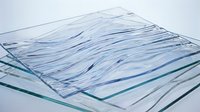 Stack of textured glass panels with wave patterns, showcasing transparency and modern industrial design for architecture and construction concepts.