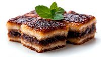 Decadent chocolate caramel layered dessert bars with fresh mint garnish on white background, perfect for bakery menus and sweet treat promotions.