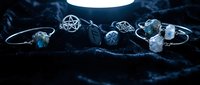 Mystical silver jewelry collection with labradorite stones and runic pentagram pendants on dark velvet, illuminated by soft moonlight glow.