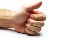 Male hand showing thumbs up gesture against white background, isolated close-up view demonstrating positive approval and success concept.