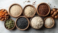 Assortment of healthy grains, seeds and nuts in wooden bowls on light background, raw superfoods for balanced nutrition.