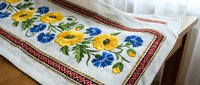 Traditional Ukrainian embroidered table runner with yellow and blue floral pattern on white linen fabric featuring folk art design for home decor.