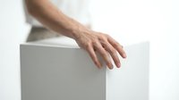 Male hand resting on white cube box against neutral background, isolated on white for product mockup, packaging design, and commercial advertising use.