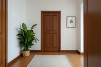 Minimalist home entrance hallway with wooden door, potted green plant, neutral area rug, and botanical wall art creating a serene welcome space.