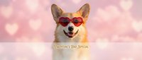 Adorable corgi dog wearing red heart-shaped sunglasses smiling at camera against pink bokeh background with heart shapes for Valentine's Day celebration.