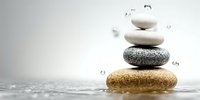 Balanced zen stones stacked in harmony with water droplets creating serene spa atmosphere for wellness and meditation practices.