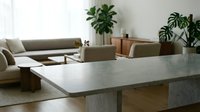 Modern minimalist living room interior with concrete dining table, beige sectional sofa, and green houseplants creating serene contemporary home decor.