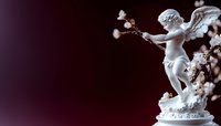 White porcelain cupid figurine with wings holding bow and arrow, surrounded by delicate floral elements against dark burgundy background, romantic decorative art piece.