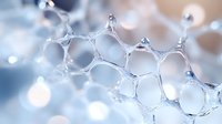 Macro photography of soap bubbles forming delicate honeycomb pattern with soft blue tones and bokeh effect, showing natural geometric shapes and light reflections.