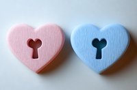 Pink and blue heart shapes with keyhole cutouts on light background, symbolizing romance, gender reveal concepts, and relationship connection.