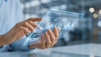 Professional businessman using transparent digital tablet with holographic financial data display and analytics charts in modern office environment.