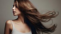 Young woman with flowing brown hair in motion against neutral background wearing white tank top, showcasing natural beauty and hair movement for beauty and fashion.