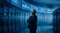 Middle-aged Caucasian businessman analyzing data visualizations in modern server room with holographic displays and blue lighting for technology presentations.