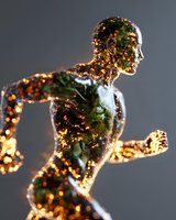 Glowing translucent male figure in running pose with golden light effects and green internal illumination against dark background, representing human energy and motion.