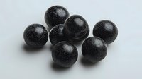 Black glittery spheres arranged on light gray background, shiny decorative balls with sparkly texture and reflective surface create elegant composition.