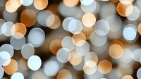 Soft glowing bokeh lights creating dreamy abstract background pattern in warm orange and cool blue tones, defocused circular light effects.
