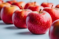 Fresh red apples arranged in rows on light background, showcasing vibrant color and texture for healthy eating concepts and food photography.