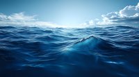 Deep blue ocean waves roll under dramatic cloudy sky, sunlight reflecting off turbulent seawater surface creating dynamic patterns and textures in marine landscape.