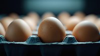 Fresh brown chicken eggs in blue carton holder against dark background, selective focus on center egg, macro food photography for packaging design.