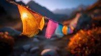 Colorful prayer flags fluttering in mountain breeze at sunset, creating spiritual atmosphere against dramatic Himalayan landscape backdrop.