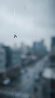 Raindrops on glass window with blurred urban cityscape background during stormy weather creating moody atmospheric scene for seasonal concepts.