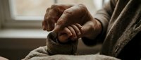 Elderly hands holding warm tea cup by window, senior person enjoying hot beverage indoors, cozy morning ritual, comfort and relaxation at home.